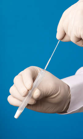 Doctor hands with hyssop and transport vial, process for  virus analysis, blue background.の写真素材