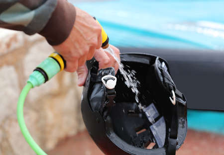 black rider helmet cleaning with water hose, kite windfoil backgroundの写真素材