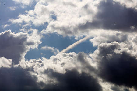 sky with storm clouds and chemtrail airplane contrailの写真素材