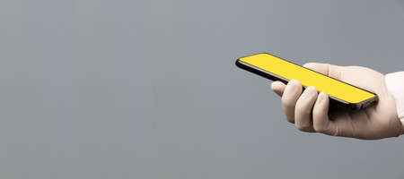 black phone in doctor hand with yellow screen for mockup, gray background