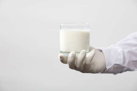 hands with glove holding glass of milk, white backgroundの写真素材