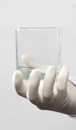 hands with glove holding empty glass glass, white backgroundの写真素材