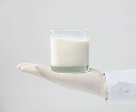 hands with glove holding glass of milk, white backgroundの写真素材