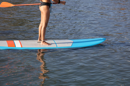 Adventurous girl on a paddle board is paddeling during a bright and vibrant sunsetの写真素材