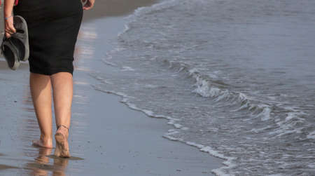woman feet walking on the beach at sunsetの写真素材