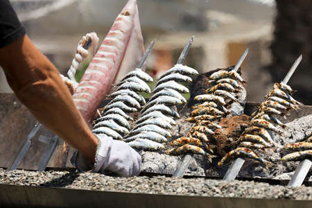squid in man's hand, fish spit on fire, beach background,の写真素材