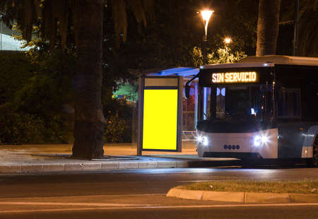 Billboard with light in the city center at night, with bus (text, no service in spanish)の写真素材