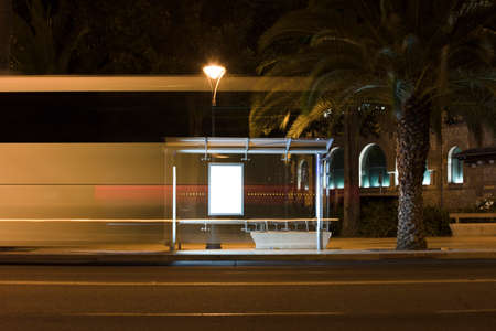 Billboard with light in the city center at night, with bus in motionの写真素材