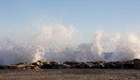 Waves splashed over rocks on a very windy day at sunset (golden hour).の写真素材
