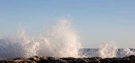 Waves splashed over rocks on a very windy day at sunset (golden hour).の写真素材