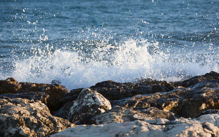 Waves splashed over rocks on a very windy day at sunset (golden hour).の写真素材