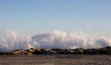 Waves splashed over rocks on a very windy day at sunset (golden hour).の写真素材