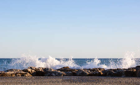 Waves splashed over rocks on a very windy day at sunset (golden hour).の写真素材