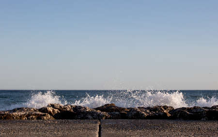 Waves splashed over rocks on a very windy day at sunset (golden hour).の写真素材
