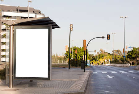 White blank vertical billboard at the bus stop on the city street. In the background of buses and roads. Sketch. Poster on the street next to the roadの写真素材