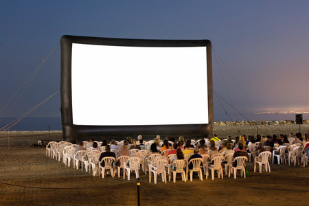 An open-air cinema on the beach at sunset. with chairs, and unrecognizable peopleの写真素材