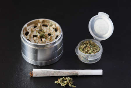 Grinder for marijuana, with joint and container dispenser, dark backgroundの写真素材