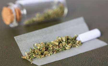 chopped marijuana, on cigarette paper with filter and airtight glass jar storage, process to make marijuana cigar.の写真素材
