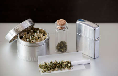 marijuana grinder with joint, transparent container and oil canister, gray and black backgroundの写真素材