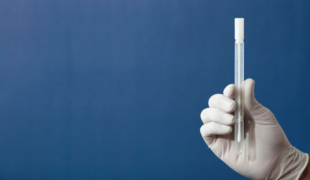buccal swab with transport medium in the hands of a doctor or nurse with white surgical gloves, blue backgroundの写真素材