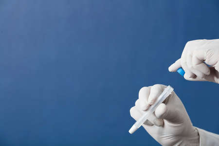 pcr analysis kit with buccal swab, nasal swab and transport medium in the hands of a doctor or nurse with white surgical gloves, blue backgroundの写真素材