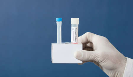 pcr kit in the hands of a doctor with surgical gloves, medium transport tubes in cardboard support, blue backgroundの写真素材