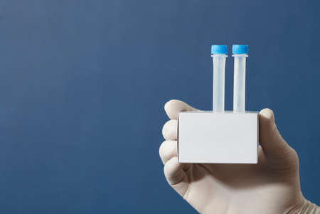 pcr kit in the hands of a doctor with surgical gloves, medium transport tubes in cardboard support, blue backgroundの写真素材