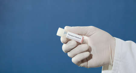 transport vial for pcr test, in the hands of a doctor, nurse, pharmacist, with blue backgroundの写真素材