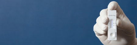 nurse or doctor performs antigen test, with blue backgroundの写真素材