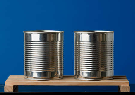 two recycled cans on wooden boards with blue backgroundの写真素材