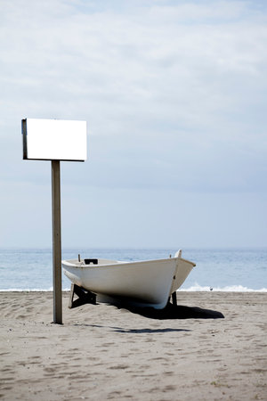 blank sign with lonely boat on the beach sandの写真素材