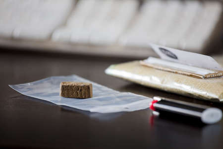portion of hashish on plastic bag, with lighter and packet of tobacco in the backgroundの写真素材