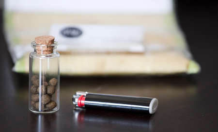 hashish in a glass jar with a lighter or tobacco at the bottomの写真素材