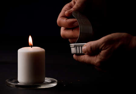concept of energy blackout, lit candle, with can of preserves in man's hands, energy poverty. (focus on candle)の写真素材