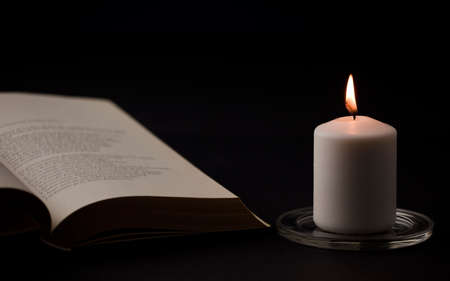 candles with flame, and reading book on desk, black background. (focus on candle).の写真素材