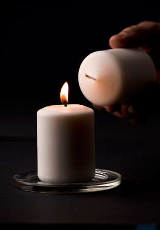 burning candle with flame, man's hands lighting candle, black background. (focus on candle).の写真素材