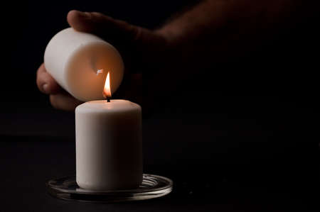 burning candle with flame, man's hands lighting candle, black background. (focus on candle).の写真素材