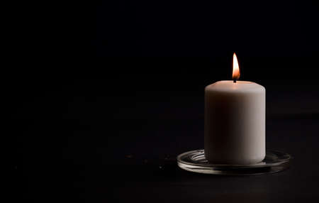 burning candle with flame, man's hands lighting candle, black background. (focus on candle)の写真素材
