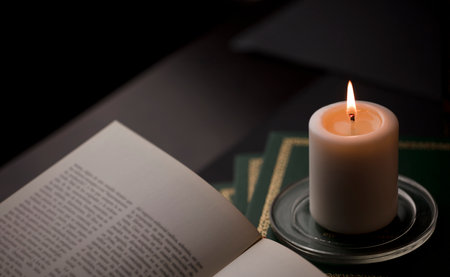 candles with flame, and reading book on desk, black background. (focus on candle).の写真素材