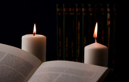 candles with flame, and reading book on desk, black background. (focus on candle).の写真素材