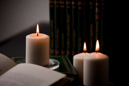 candles with flame, and reading book on desk, black background. (focus on candle).の写真素材