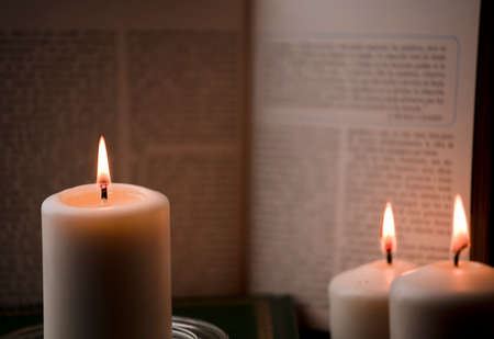 candles with flame, and reading book on desk, black background. (focus on candle).の写真素材