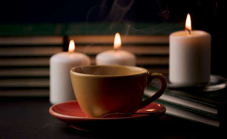 cup of tea with hot smoke and three burning candles. on the desk at home, power outage (focus on cup).の写真素材