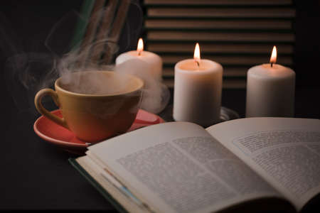 cup of tea with hot smoke and lit candle. on the desk at home, power outage (focus on cup).の写真素材
