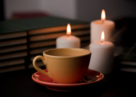cup of tea with hot smoke and three burning candles. on the desk at home, power outage (focus on cup).の写真素材