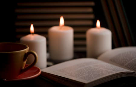cup of tea with hot smoke and three burning candles. on the desk at home, power outage (focus on cup).の写真素材