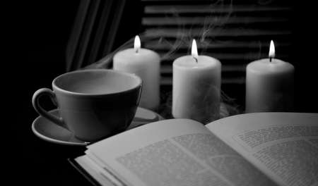 cup of hot coffee with book and candles in the background, black and white. (focus on cup)の写真素材