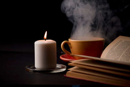 home study table with candles with flame and reading book, (focus on candle).の写真素材