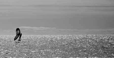 sportsman practices wing foil, in the mediterranean sea, backlight, black and white.の写真素材