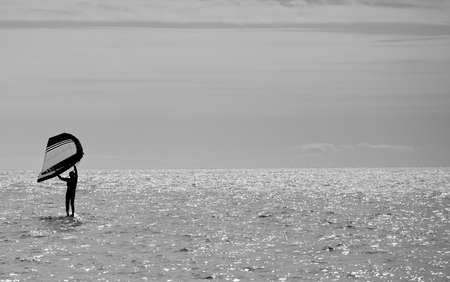 sportsman practices wing foil, in the mediterranean sea, backlight, black and white.の写真素材
